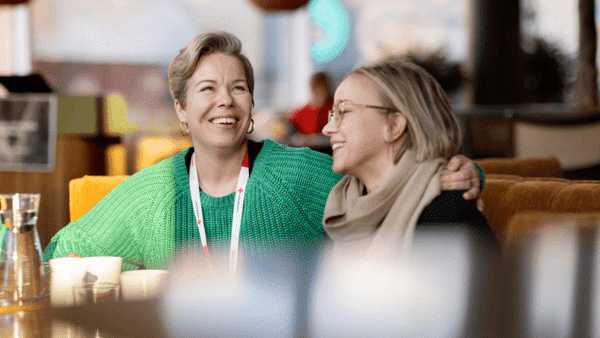 Bild på två kvinnor som skrattar och håller om varandra. Bild från Röda Korset Umeåkretsen